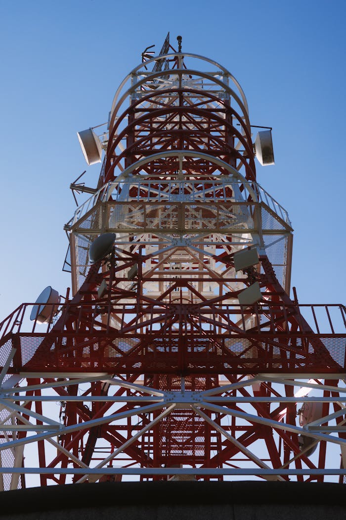 Tall red and white communication tower against clear blue sky, showcasing modern infrastructure